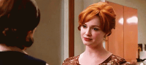 a woman with red hair is looking at another woman in a room .