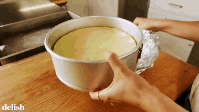 a person is wrapping a cake in tin foil and the word delish is on the bottom right