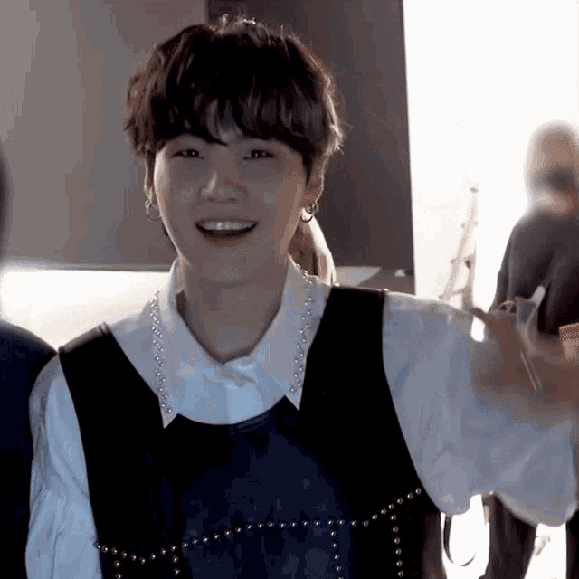 a man wearing a white shirt and a black vest smiles