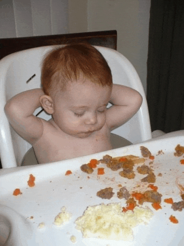 a baby is sitting in a high chair with his hands on his head