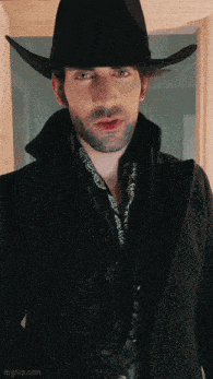 a man wearing a black cowboy hat and a black coat