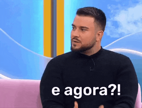 a man with a beard is sitting on a couch with the words e agora written on his face