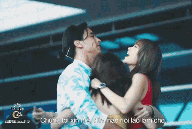 a man is holding two women in his arms with the words " chúng tôi xin thế " written in the background