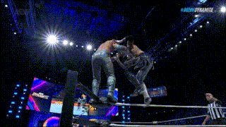 a wrestler is doing a handstand in a wrestling ring with a sign that says dynamite