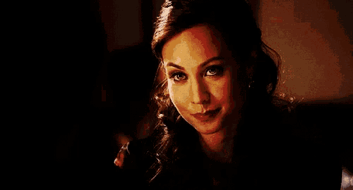 a close up of a woman 's face with a smile on her face in a dark room .