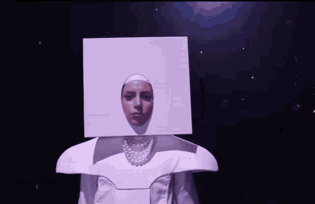 a woman wearing a white costume with a box on her head