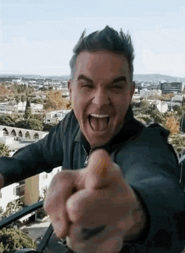 a man is pointing at the camera with his tongue out