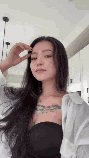 a woman with long hair and a tattoo on her chest is wearing a white shirt