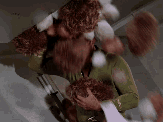 a man in a green sweater is holding a stuffed animal in his hands