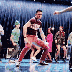 a man is dancing on a stage with a group of people .