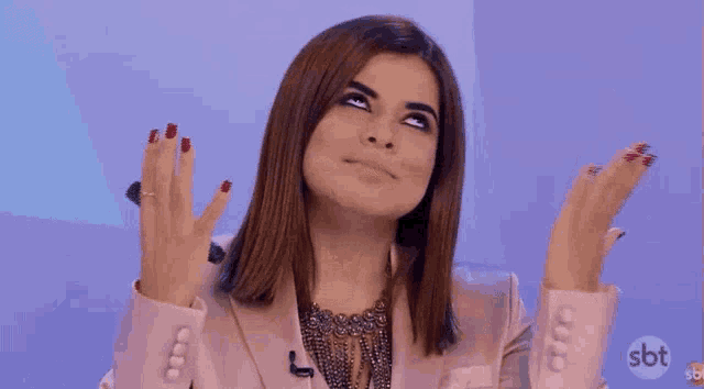 a woman in a pink jacket is making a funny face with her hands in the air .