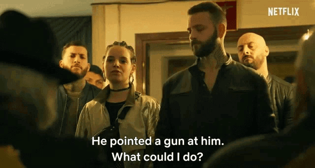 a group of people are standing in a room and a man says he pointed a gun at him .