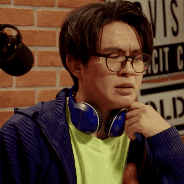 a man wearing glasses and blue headphones stands in front of a sign that says old circuit