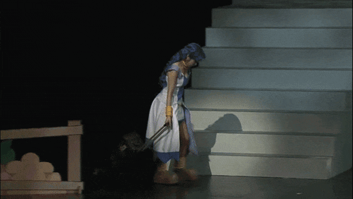 a woman in a blue and white dress is walking down stairs with a suitcase