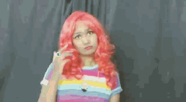 a woman with red hair is wearing a rainbow shirt and a ring .