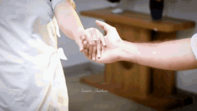 a woman holds a man 's hand with a ring in her finger