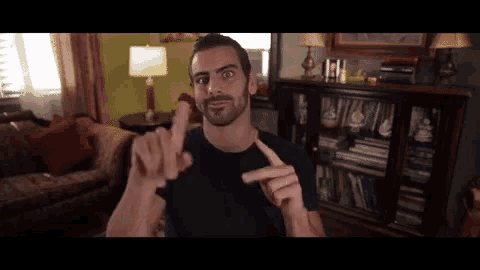 a man in a living room is pointing at something with his fingers
