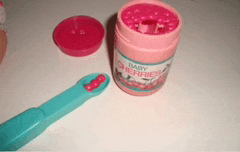 a pink container of baby cherry juice next to a blue toothbrush