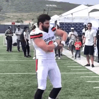 a man in a cleveland browns jersey is standing on a football field .
