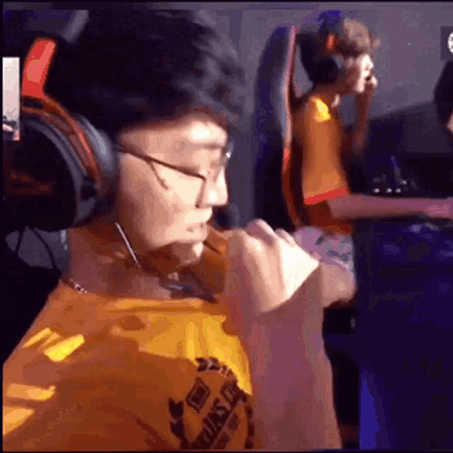 a man wearing headphones and glasses is sitting in a chair playing a video game .