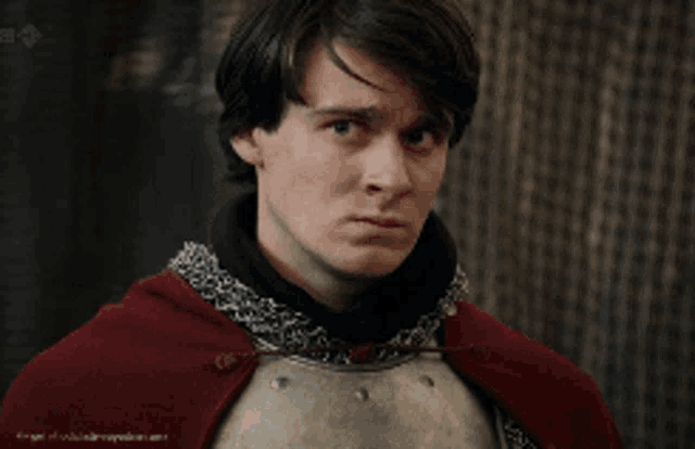 a young man wearing armor and a red cape