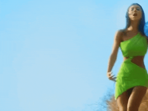 a woman in a green dress is standing in a field .