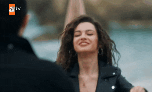 a woman in a black leather jacket is smiling and looking at a man in a black jacket