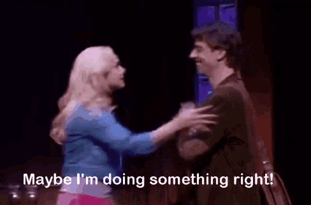 a woman is standing next to a man on a stage and says maybe i 'm doing something right ..