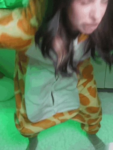 a woman in a giraffe costume is squatting down in front of a green light