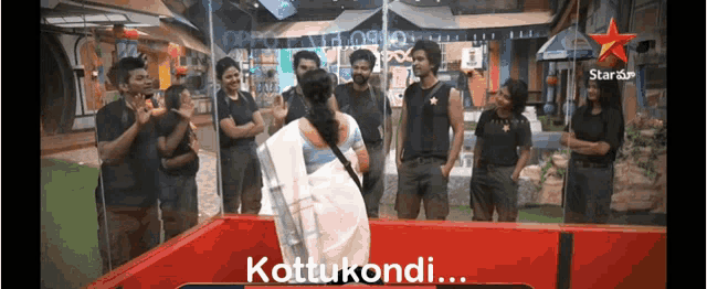 a group of people are standing around a woman in a white saree with the words kottukondi written on the bottom