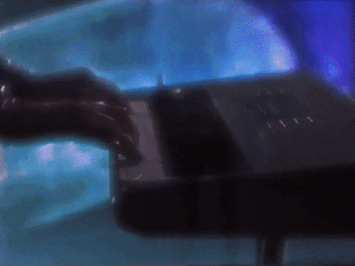 a person is typing on a keyboard with a blue light behind them