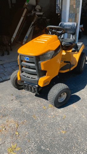 a yellow lawn mower is parked in a driveway in front of a garage