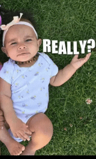 a baby is laying in the grass with the words " really " behind her