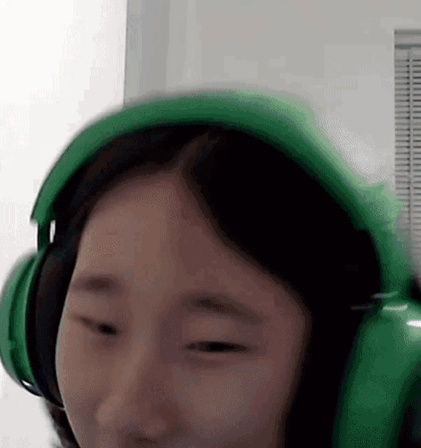 a woman wearing green headphones is making a face .