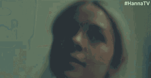 a close up of a woman holding her head while looking at herself in the mirror .