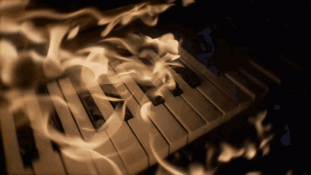 a close up of a piano keyboard with flames coming out of it