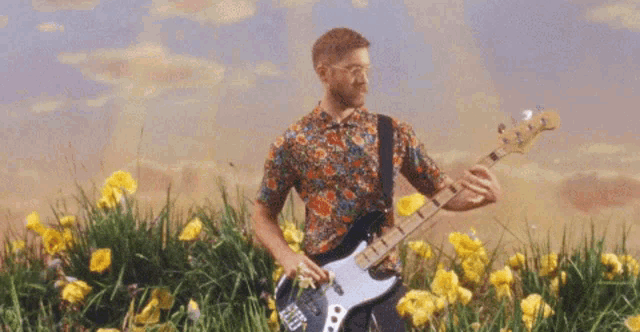a man playing a guitar in a field of flowers