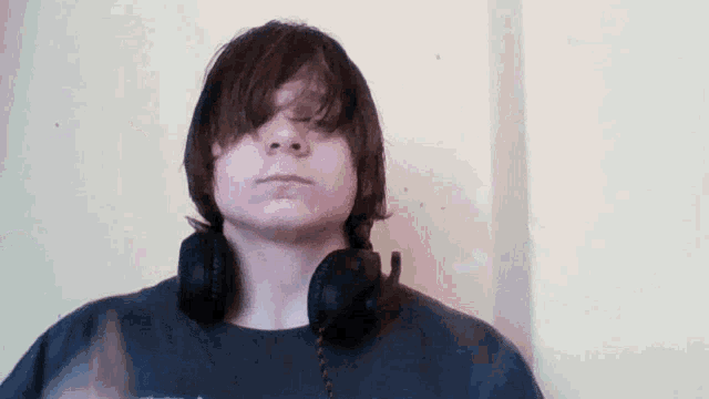 a young man wearing headphones and a black shirt is looking at the camera