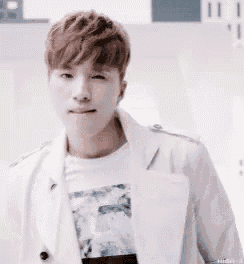 a close up of a young man wearing a white jacket and a white shirt .