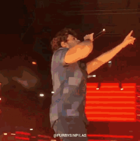 a man singing into a microphone with his arms in the air