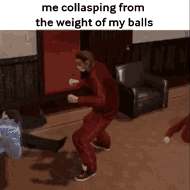 a man in a red tracksuit is dancing in a hallway while another man is laying on the floor .