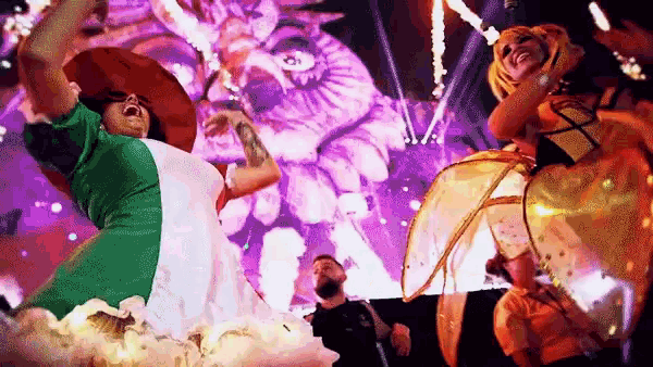 a woman in a green and white dress is dancing in front of a large screen