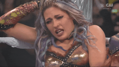 a woman in a wrestling ring with a cw logo on the bottom
