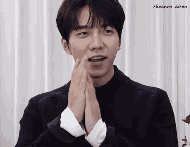 a young man with braces on his teeth is holding his hands together in front of his face .