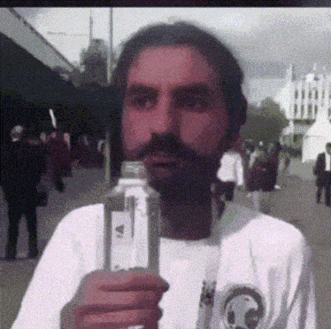a man with a beard is holding a bottle in his hand