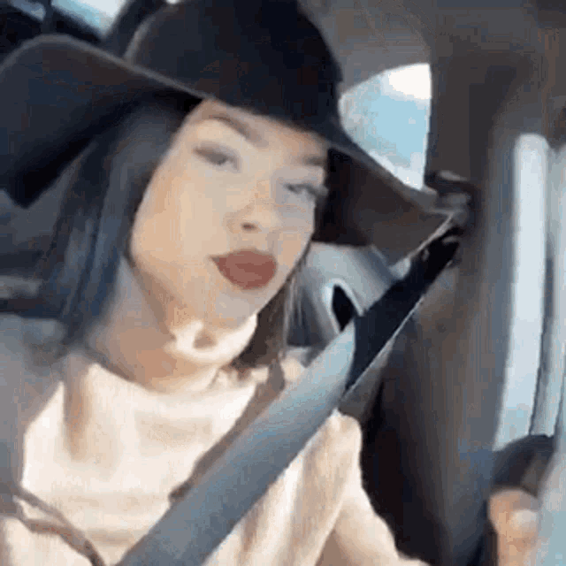 a woman wearing a cowboy hat is sitting in a car with a seat belt .