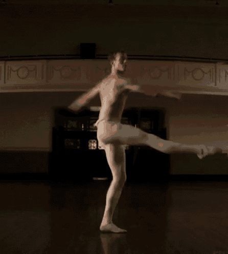 a man without a shirt is standing on one leg with his arms outstretched