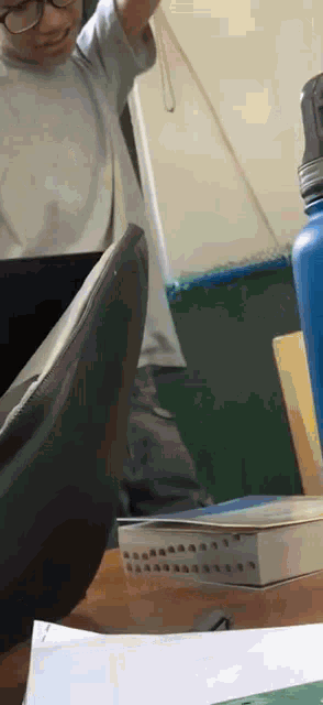 a person is sitting at a desk with a book and a blue water bottle