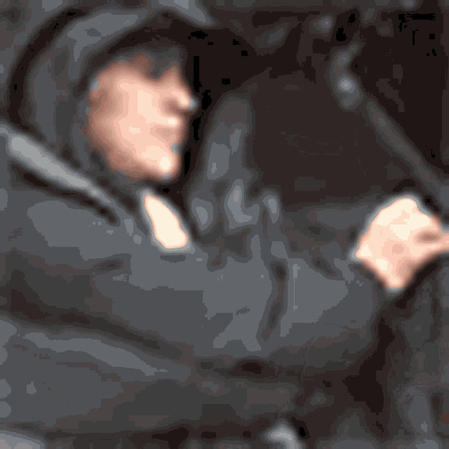 a man in a hooded jacket is holding a gun in his hand .