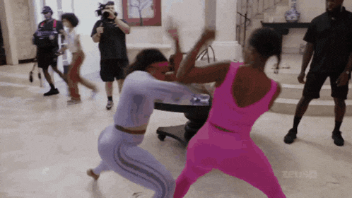 a woman in a pink outfit is fighting another woman